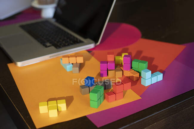 Vista ad alto angolo di carta multicolore, laptop e blocchi colorati sul tavolo — Foto stock