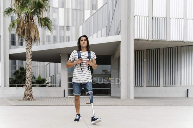 Homme avec un membre artificiel marchant contre le bâtiment en ville — Photo de stock
