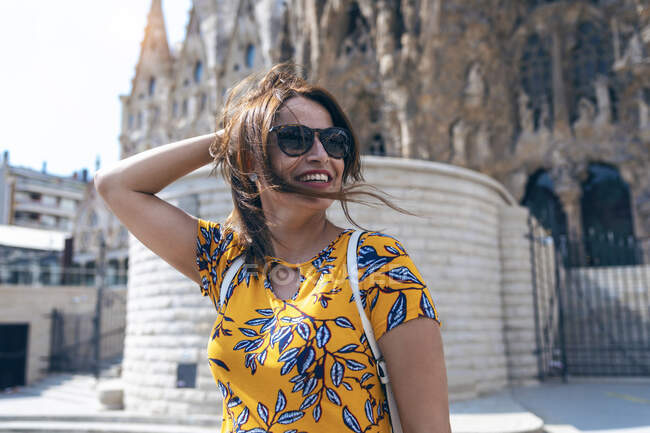 Metà donna adulta sorridente mentre in piedi contro la Sagrada Familia a Barcellona, Catalogna, Spagna — Foto stock