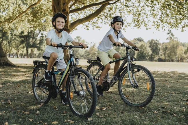 Fratelli con ciclismo nel parco pubblico nella giornata di sole — Foto stock