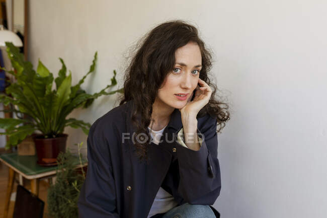 Bella donna con mano sul mento seduta a casa — Foto stock