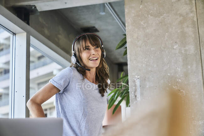 Smiling woman wearing headphones looking away while standing at home — Stock Photo