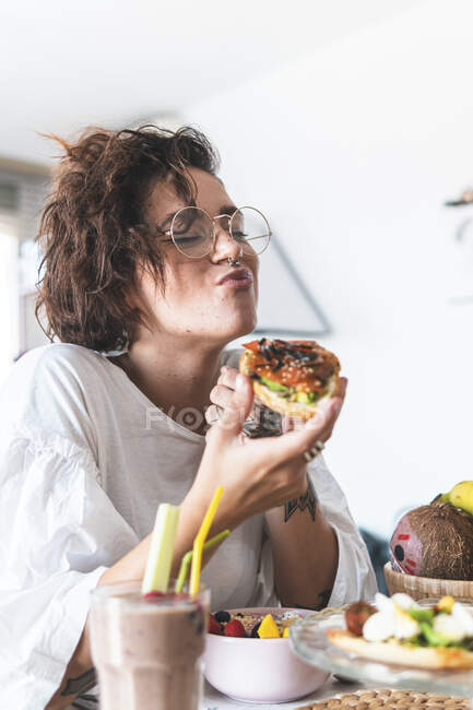Portrait de jeune femme portant des lunettes et anneau de nez petit déjeuner — Photo de stock