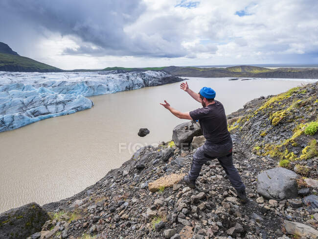 Hombre adulto medio arrojando piedra en el lago en el glaciar Svinafellsjokull, Islandia - foto de stock