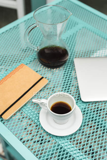 Notizblock, Laptop, Kaffeetasse und Topf auf dem Tisch im Café — Stockfoto