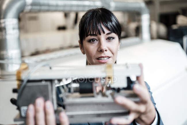 Businesswoman investigating while looking at machine part in industry — Stock Photo