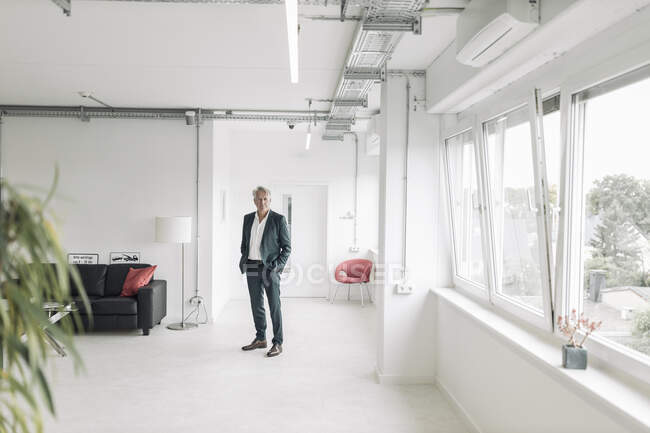 Бизнесмен с руками в карманах стоит в новом офисе — стоковое фото