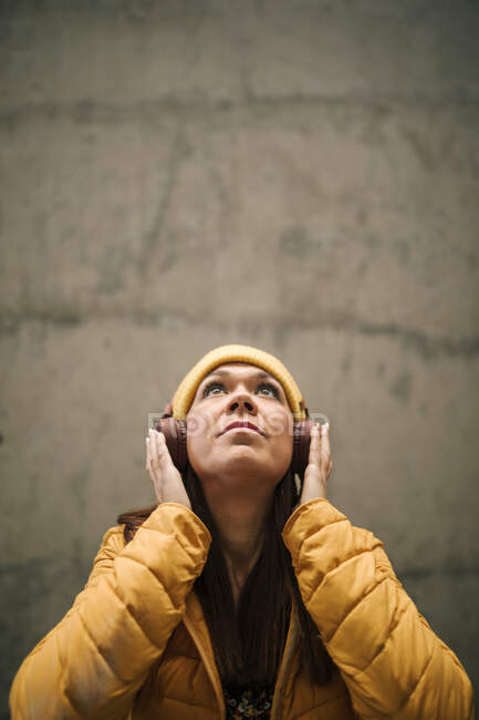 Reife Frau schaut auf, während sie Musik über Kopfhörer hört — Stockfoto