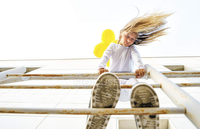 Visão de baixo ângulo da menina de pé sobre trilhos com cabelos desarrumados durante o dia ensolarado — Fotografia de Stock