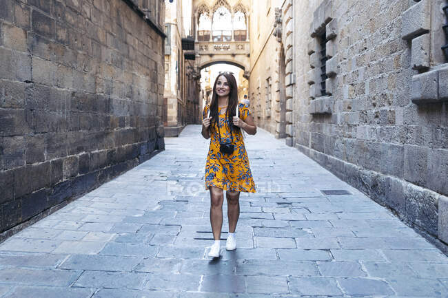 Mujer adulta sonriendo mientras camina en el Barrio Gótico, Barcelona, Cataluña, España - foto de stock
