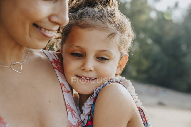 Close-up of mother and daughter embracing at beach on sunny day — Stock Photo