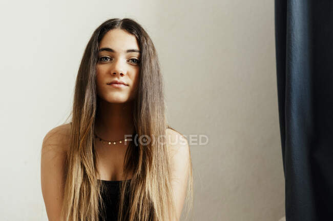 Длинные волосы девушка сидит у белой стены дома — стоковое фото