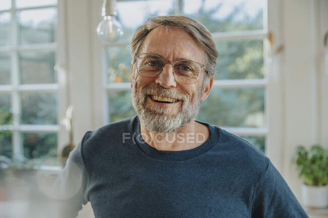 Homme mûr riant tout en se tenant à la maison — Photo de stock