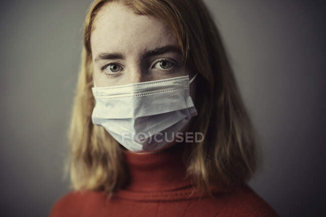 Adolescente usando máscara protetora enquanto está contra fundo cinza — Fotografia de Stock