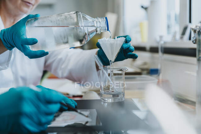 Учені, стоячи в лабораторії, фільтрують рідину. — стокове фото