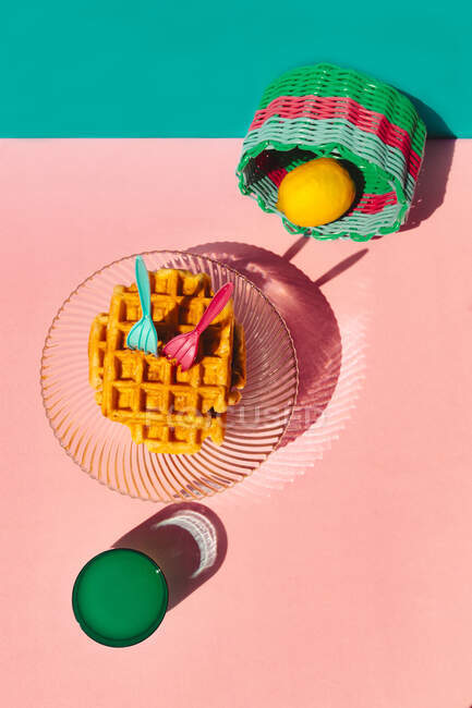 Vista de ángulo alto de waffle, limón en cesta, jugo guardado en la mesa - foto de stock