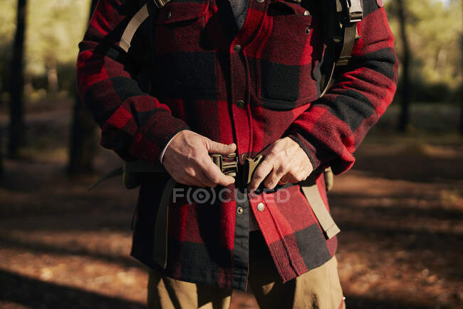 Midsection of bushcrafter fastening belt while standing in forest — Stock Photo
