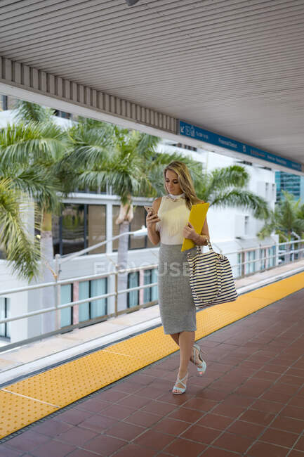 Femme entrepreneur utilisant un téléphone intelligent tout en marchant à la gare — Photo de stock