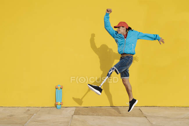 Heureux homme handicapé marchant contre le mur jaune — Photo de stock