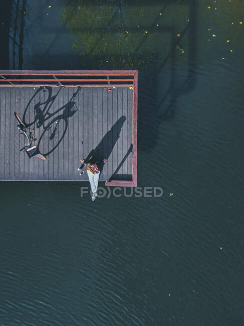 Vista aérea da jovem mulher sentada sozinha na borda do molhe costeiro — Fotografia de Stock