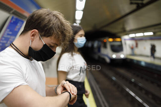 Молодий чоловік перевіряє час, стоячи поруч з жінкою на платформі метро. — стокове фото