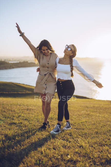 Carefree young female friends on hill against bright sky at Mirador de La Providencia, Gijon, Spain — Stock Photo