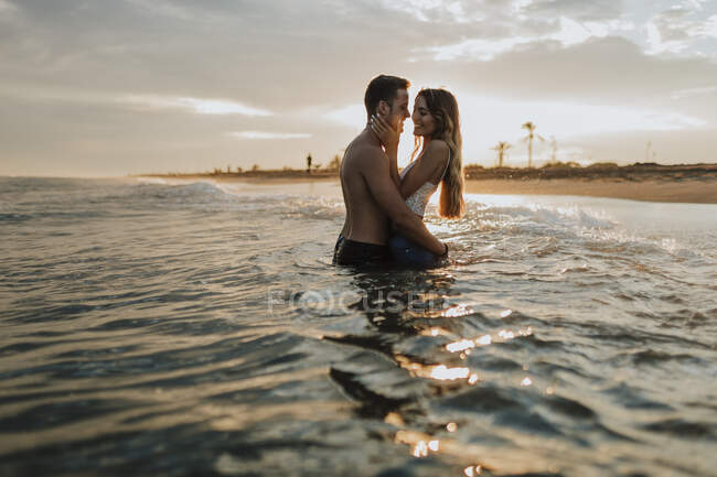 Couple romantique debout dans l'eau à la plage — Photo de stock