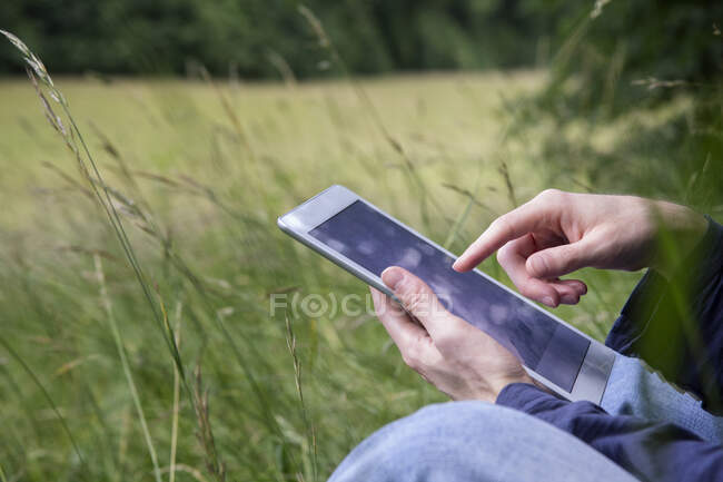 Mature man using digital tablet while sitting in nature — Stock Photo