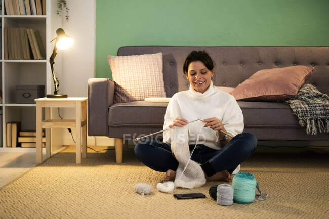 Feliz mujer adulta media tejiendo lana en casa - foto de stock