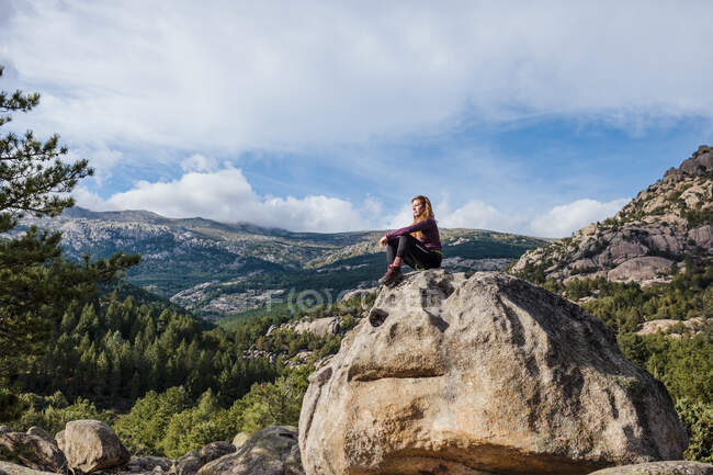 Trekker looking at view while sitting on rock against sky at La Pedriza, Madrid, Spain — Stock Photo