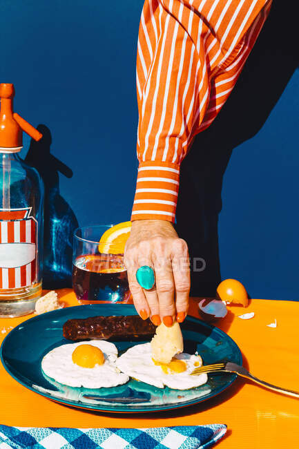Arm of woman eating fried eggs with chorizo — Stock Photo