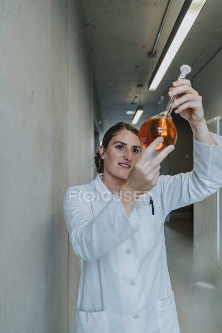Chercheuse examinant une solution liquide debout dans le couloir de la clinique — Photo de stock