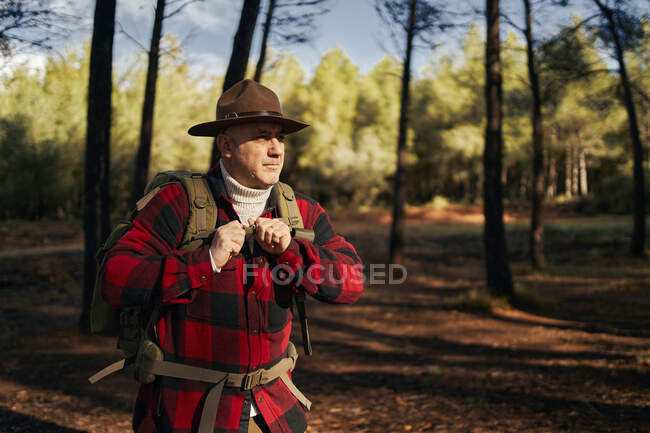 Bushcrafter portant un chapeau debout dans la forêt — Photo de stock