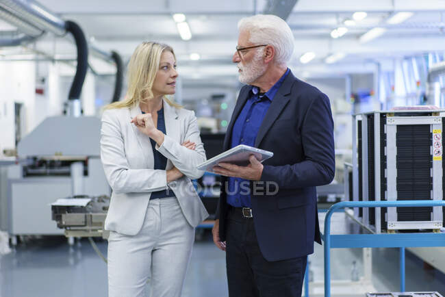 Fiduciosa donna d'affari e uomo d'affari che si guardano mentre discutono in fabbrica — Foto stock