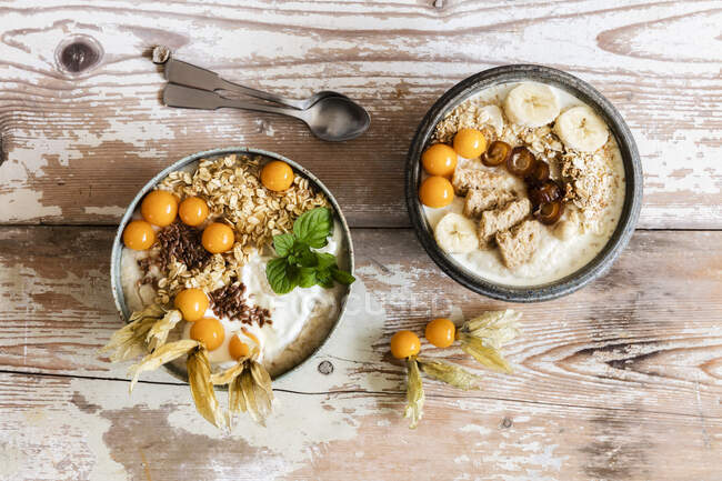 Two bowls of porridge with oats, flax seed, winter cherries and bananas — Stock Photo