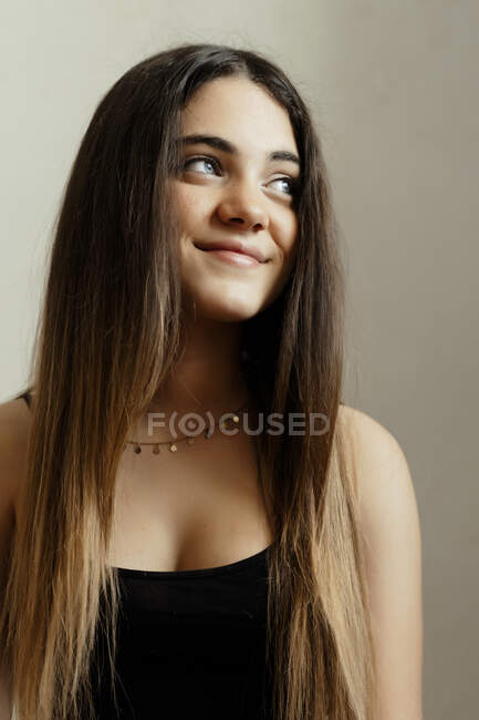 Lächelndes Mädchen mit langen Haaren sitzt zu Hause an weißer Wand — Stockfoto