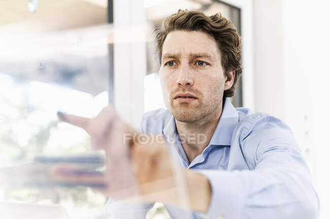 Mittlerer erwachsener Mann zeigt im Büro auf Glasmaterial — Stockfoto