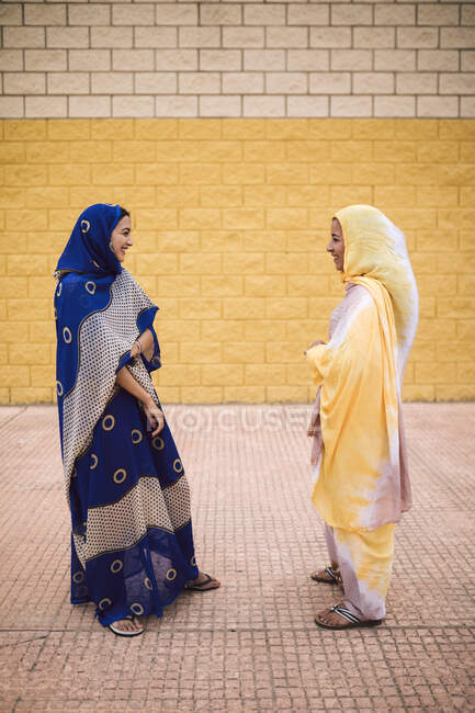 Friends talking with each other while standing by wall — Stock Photo