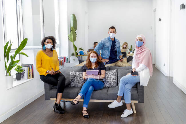 Роботодавці носять маску обличчя, підтримуючи соціальну дистанцію, сидячи з колегою на задньому плані в офісі під час COVID-19. — стокове фото