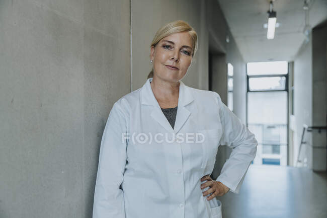 Scienziato con mano sull'anca in piedi nel corridoio della clinica — Foto stock