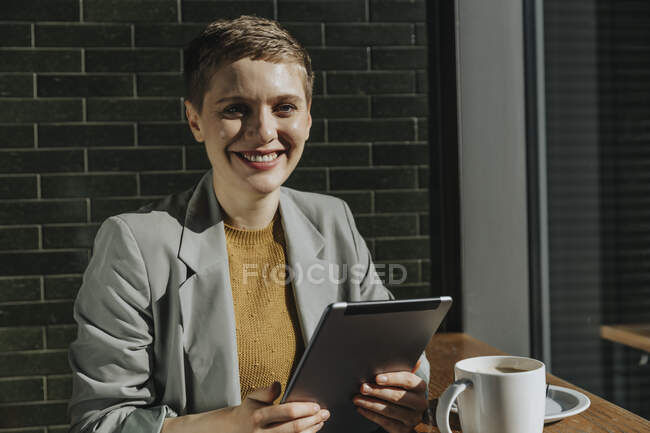 Mujer usando tableta digital mientras está sentado en la cafetería en el día soleado - foto de stock