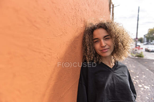 Junge Frau lehnt an orangefarbener Wand — Stockfoto