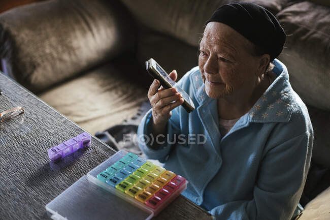 Senior mulher enviando correio de voz através do telefone celular na sala de estar — Fotografia de Stock
