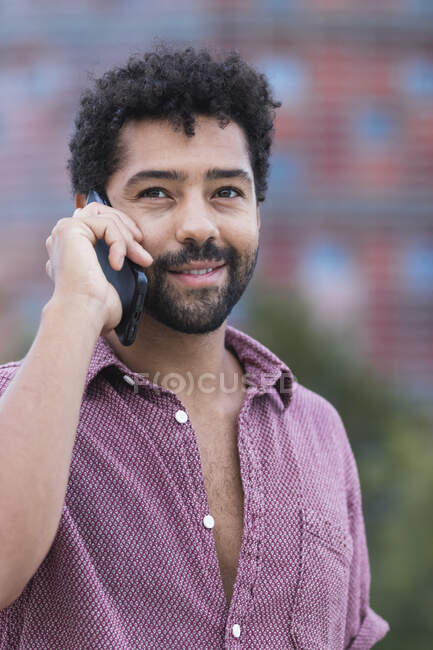 Uomo sorridente che parla sul cellulare in città — Foto stock