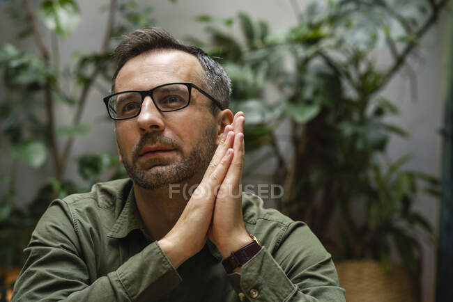 Pensativo hombre de negocios sentado con las manos apretadas en la cafetería - foto de stock
