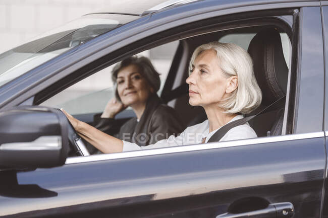 Colleague sitting with businesswoman while driving car in city — Stock Photo