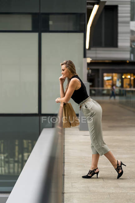 Donna premurosa con la testa in mano appoggiata alla ringhiera mentre in piedi al centro commerciale — Foto stock