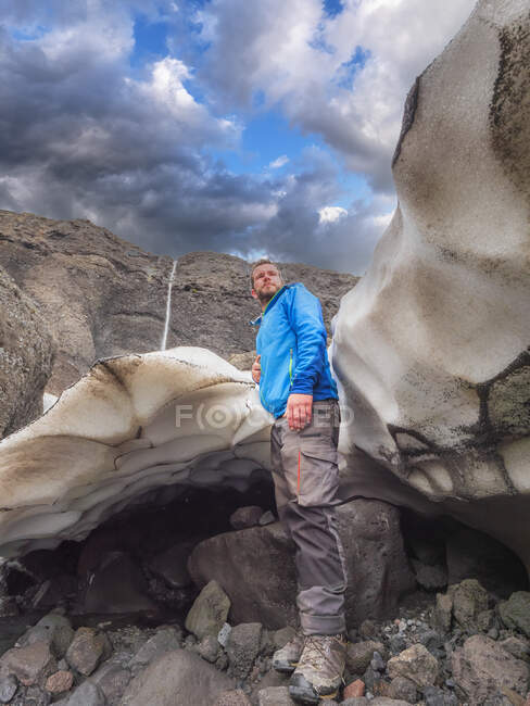 Touriste masculin debout sur le rocher à Langjokull contre un ciel nuageux, Islande — Photo de stock