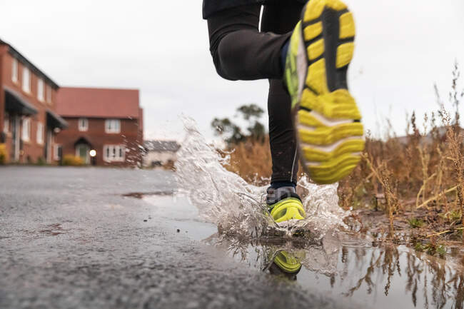 Niedriger Teil der Menschen läuft während der Regenzeit in Wasserpfütze — Stockfoto