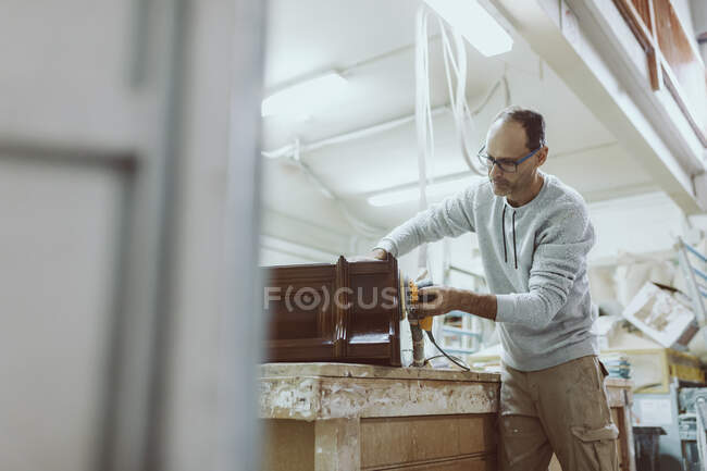 Ремесленник, стоящий в мастерской с помощью шлифовального шлифовального станка — стоковое фото